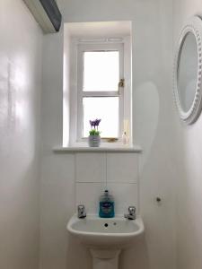 a white bathroom with a sink and a window at Delight Marvel - Cades Place in Maidstone