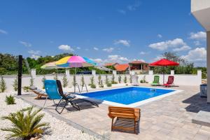 una piscina con sillas y sombrillas en un patio en Villa Adriatic Sunset, en Jadrija