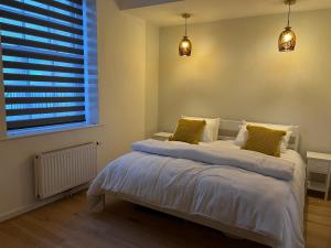 a bedroom with a bed with white sheets and yellow pillows at SeaViewApartment in Swanage