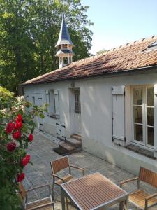 a white building with chairs and a table and a tower at Bords de Seine et forêt proche de Paris et Fontainebleau in Bois-le-Roi