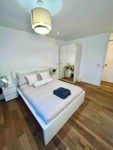 - une chambre avec un grand lit blanc et une serviette bleue dans l'établissement Lovely 1 Bed, Northolt Station, à Northolt