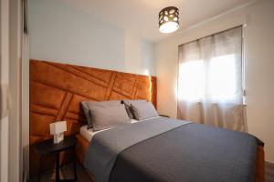 - une chambre avec un lit doté d'une tête de lit en bois et d'une fenêtre dans l'établissement Boutique Apartments Blitz, à Bibinje