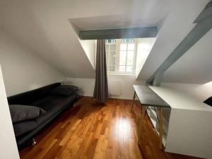 - un salon avec un canapé noir et une fenêtre dans l'établissement Appartement T2 - classé 3 étoiles - 4+2, à Bagnères-de-Bigorre