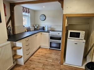 a kitchen with a white refrigerator and a microwave at Perfectly Located Pretty Cottage in Diss