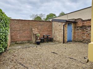 a brick wall with a picnic table and a blue door at Perfectly Located Pretty Cottage in Diss
