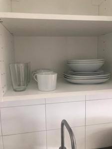 a kitchen shelf with plates and bowls and a sink at Nice Entire Semi - Attached House - M in Umeå