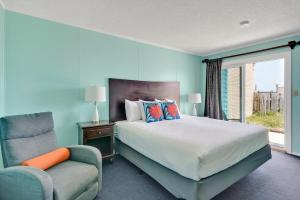 a bedroom with a bed and a chair and a window at Admiral's Quarters in Kure Beach