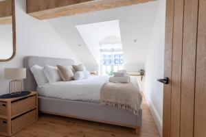 a white bedroom with a bed and a window at Boutique Old Sea Stable - 1 minute from beach in Tynemouth