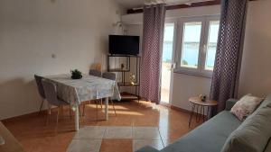 a living room with a table with chairs and a television at Apartments Donadic I, Caska in Novalja