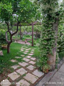 a stone pathway in a garden with trees and a pergola at Corte Piri in Tricase