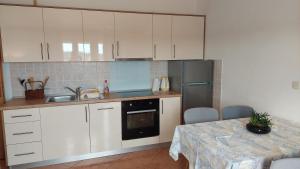 a kitchen with white cabinets and a sink and a table at Apartments Donadic I, Caska in Novalja