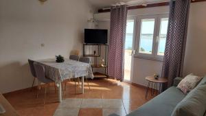 a living room with a table with chairs and a television at Apartments Donadic I, Caska in Novalja