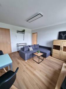 a living room with a blue couch and a table at Gemütliche Wohnung bei Leipzig in Schkeuditz +3 photos