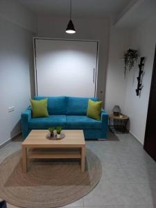 uma sala de estar com um sofá azul e uma mesa de centro em Το Κεντρικό διαμέρισμα της πόλης em Lárissa