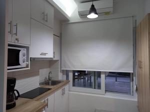 a kitchen with a sink and a microwave and a window at Το Κεντρικό διαμέρισμα της πόλης in Larisa +12 photos