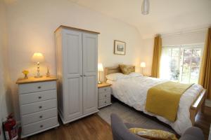 a bedroom with a bed and a dresser at Almond Tree Cottage in Lanteglos