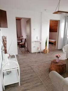a living room with white walls and a wooden floor at Marianna Apartman in Gyenesdiás