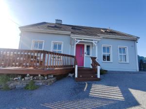 une maison blanche avec une porte rose et une terrasse couverte dans l'établissement Lanelodge -Room Only-, à Doolin