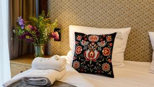 a bed with a pillow and a vase of flowers at Aparthotel Merynos in Zakopane +218 photos