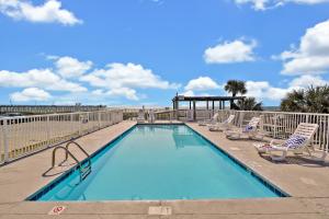 uma piscina com espreguiçadeiras e cadeiras em Admiral's Quarters em Kure Beach