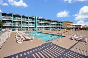 a large building with a swimming pool and lounge chairs at Admiral's Quarters in Kure Beach