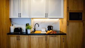 a kitchen with white cabinets and a black counter top at Aparthotel Merynos in Zakopane