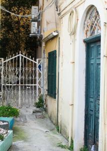 an alley with a green door and a fence at Deppy's Two-storey House in Corfu