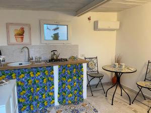 una cucina con bancone, lavandino e due tavoli di Rifugio tra gli ulivi a Marina di Ragusa