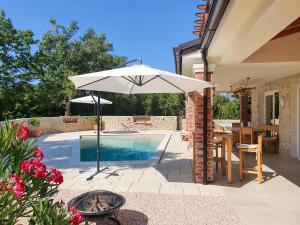 ein weißer Regenschirm neben einem Pool in der Unterkunft Villa Alara - charming villa with heated swimming pool in Milohnići