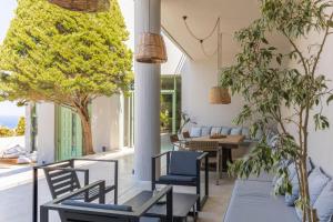 a patio with chairs and tables and trees at Mama La Roosa Luxury Retreat in Agia Pelagia