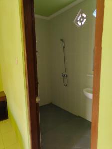 uma casa de banho com um chuveiro e um lavatório. em Berlian Inn Kuta Beach em Kuta