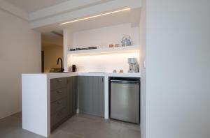 uma cozinha com balcões brancos e uma máquina de lavar louça em Korfi de Milo em Adamas