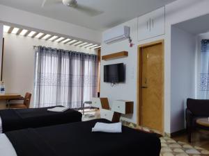 a room with two beds and a tv on the wall at Hotel Hill Ambassador in Rāngāmāti