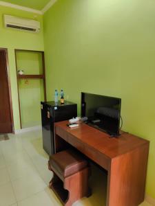 a room with a desk with a television and a stool at Berlian Inn Kuta Beach in Kuta