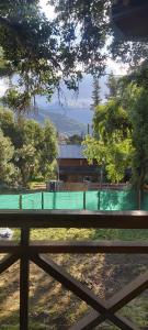 einen Zaun vor einem Feld mit einem Gebäude in der Unterkunft La Peninsula Cabaña in San Carlos de Bariloche