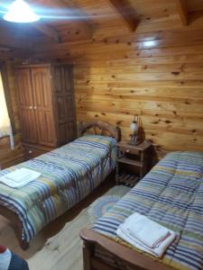 1 dormitorio con 2 camas en una cabaña de madera en La Peninsula Cabaña en San Carlos de Bariloche