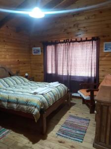 a bedroom with a bed in a log cabin at La Peninsula Cabaña in San Carlos de Bariloche