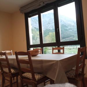 a dining room table with chairs and a large window at Lillo Home in Puebla de Lillo