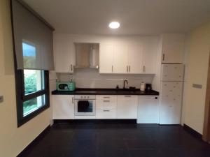 an empty kitchen with white cabinets and a window at Lillo Home in Puebla de Lillo