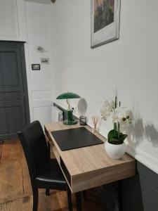 uma mesa de madeira com uma cadeira preta e uma secretária com flores em Le studio de la Clarté em Périgueux