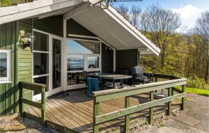 a green house with a deck with a table and chairs at Nice Home In Vejle st With 2 Bedrooms in Bredal