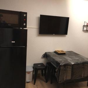 een kamer met een tafel en een tv aan de muur bij Studio Puy saint vincent 1600 in Les Prés