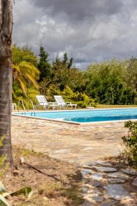a swimming pool with two lawn chairs and trees at Monte Cerro da Vigia by Vacationy in Zambujeira do Mar