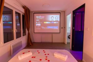 Cette chambre dispose d'un écran de projection et d'un lit avec des coeurs rouges. dans l'établissement Spa & Détente - Cinéma - Parking - Gare, à Amiens