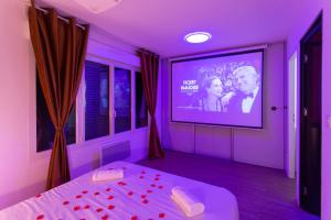 Cette chambre violette comprend un lit et une télévision. dans l'établissement Spa & Détente - Cinéma - Parking - Gare, à Amiens