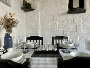 a table with plates and glasses on a white brick wall at Old Nursery in Coity