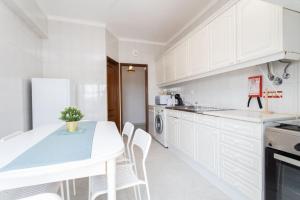een keuken met witte kasten en een tafel en stoelen bij Casa conde - Blue coast in Setúbal