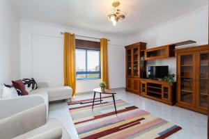 een woonkamer met een bank en een tv bij Casa conde - Blue coast in Setúbal