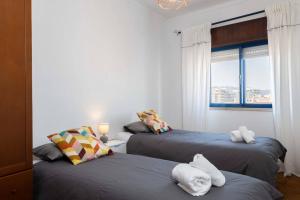 drie bedden in een kamer met een raam bij Casa conde - Blue coast in Setúbal