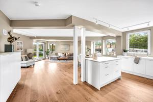 a large kitchen and living room with white cabinets at Unik plass ved Nidelva in Trondheim